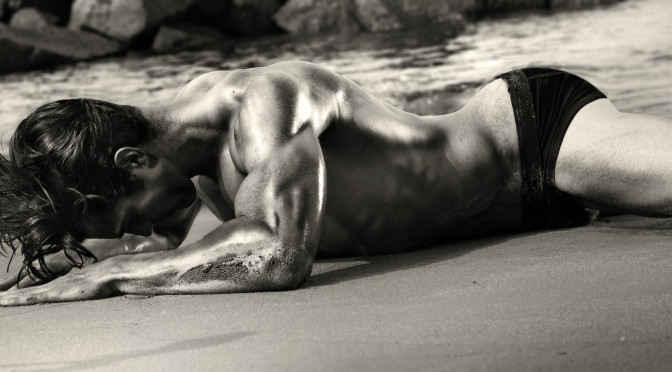 Sexy black and white image of a man crawling on the beach