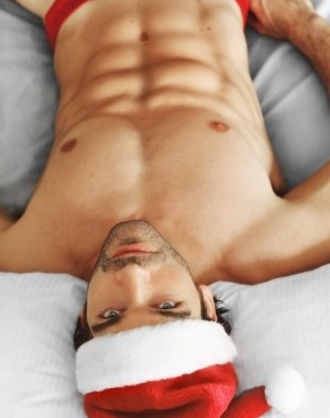 Sexy topless man in a Santa hat
