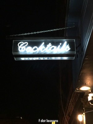Photo of a neon cocktails sign against black sky